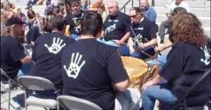 Group of Nulhegan Citizens sitting around a big drum in front of the Vermont Statehouse.