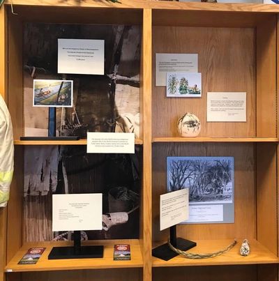 Display of Abenaki art on wooden shelves.