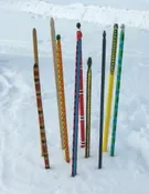 Snow snakes of many colors displayed in the snow.